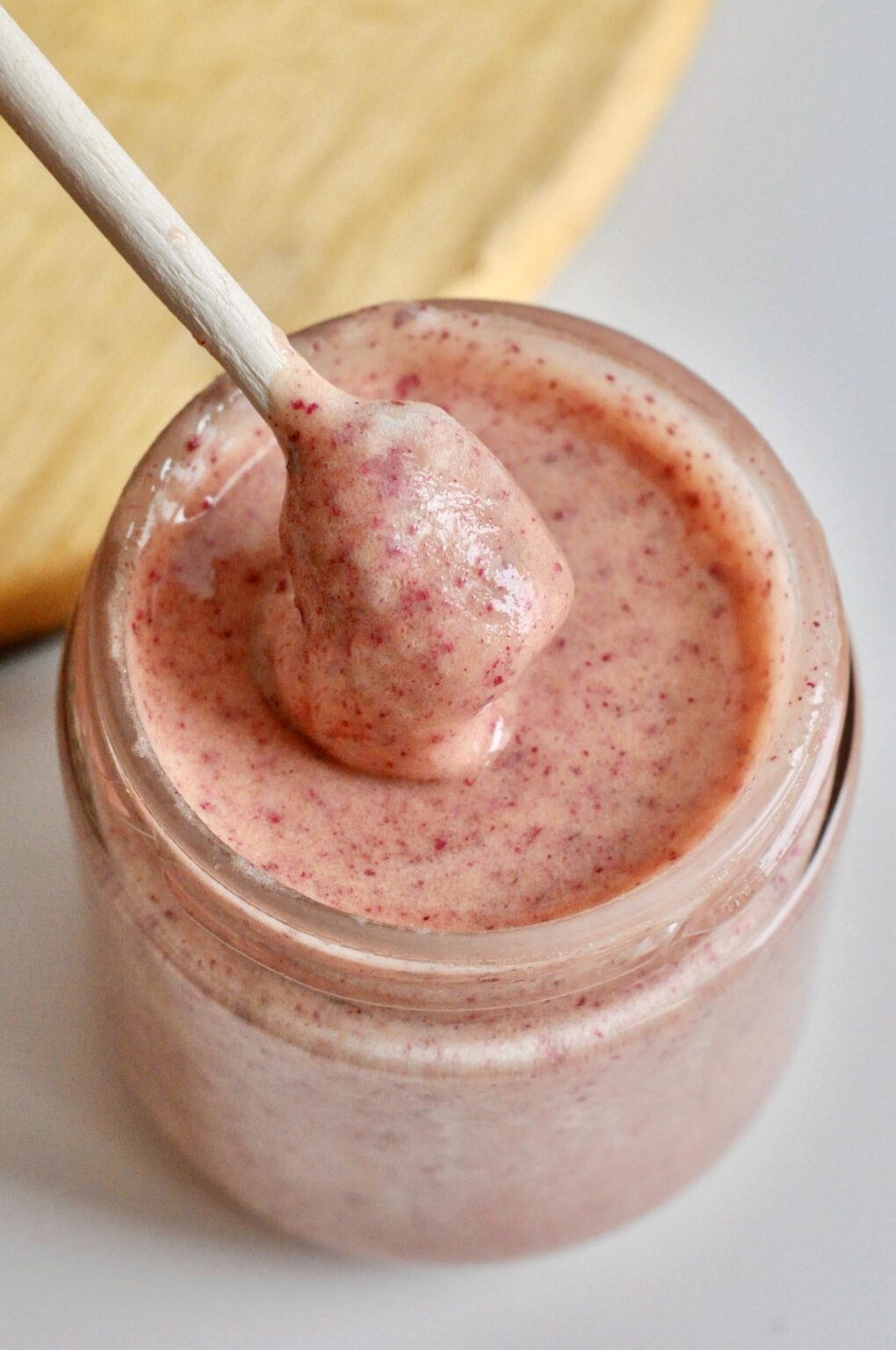 Pale pink rose cream honey speckled with berry pieces in a glass jar