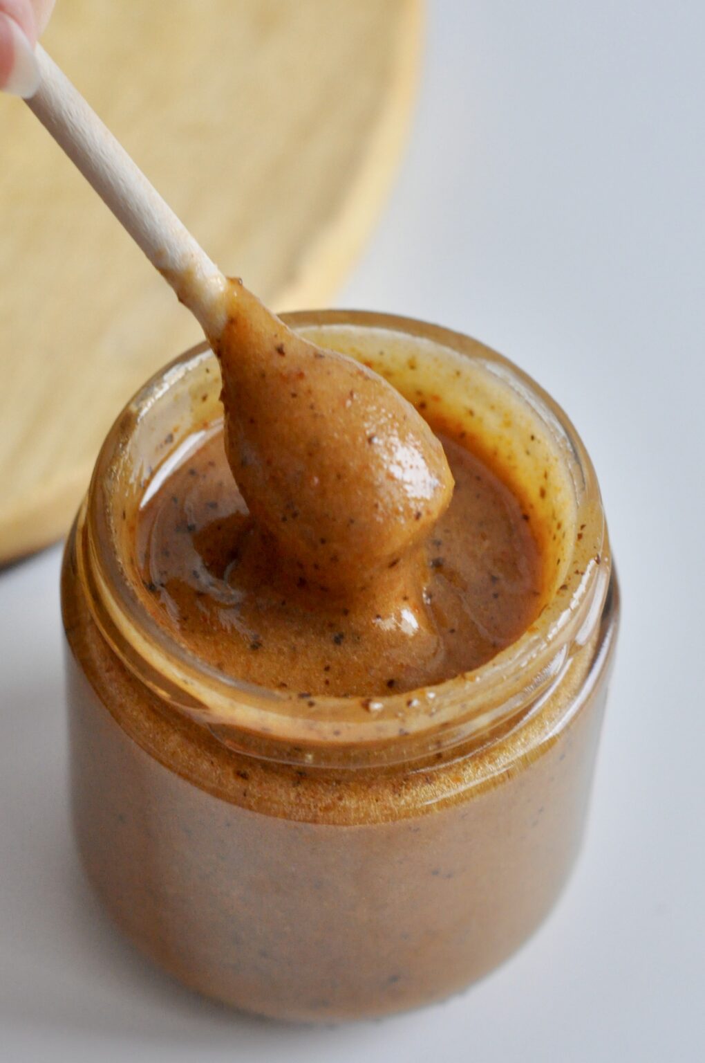 Amber sea buckthorn cream honey with vanilla flecks on a wooden dipper